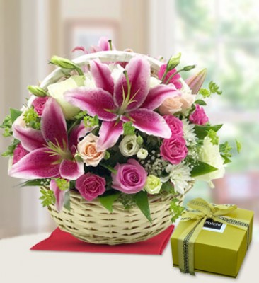 Round basket arrangement of 4 stems of pink lilies , 14 Pink Roses , 6 peach roses , 6 white roses and 2 stems of White chrysanthemums with lots of greens and gypsophillia and 250 gms Patchi chocolate Impressive Basket