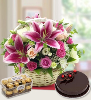 Round basket arrangement of 4 stems of pink lilies , 14 Pink Roses , 6 peach roses , 6 white roses and 2 stems of White chrysanthemums with lots of greens and gypsophillia with 16 pcs Ferrro Rocher Chocolate and 1 Kg Cake Heavenly Flowers