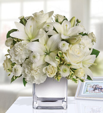 2 stems of white Lilies , 4 stems of white Roses , 4 stems of white Carnations and 2 stems of Chrysanthemum in a Glass Vase (one sided round arrangement) Love's Embrace Roses - White
