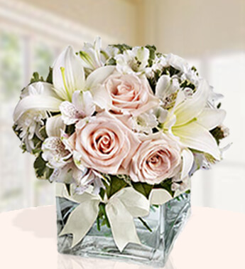 4 stems of Peach roses with 2 stems of white lilies, 2 stems of white alstroemeria and 2 stems of chrysanthemums in a cube Glass vase. (one sided round arrangement) Arrive In Style
