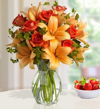 5 stems of Orange lilies and 8 Orange roses in a Glass vase Womans Alike
