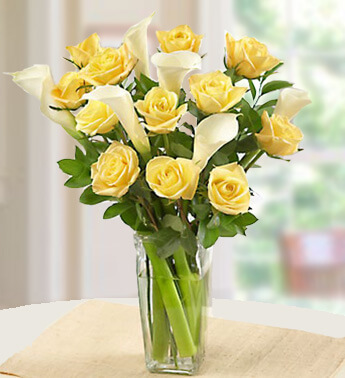 12 stems of Yellow Roses and 6 White Calla Lilies with fillers in a glass vase. Spread the Sunshine