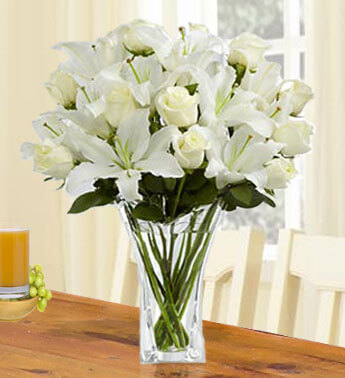 12 stems of White Roses and 5 stems of White Lilies in a glass vase. Essence of Grace