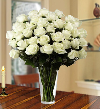 40 stems of White Roses with fillers in a glass vase. Innocent White
