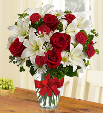 Arrangement of 5 stems of Red roses, 3 stems of White Lilies and 10 stems of Red carnations in a glass vase. (One side round arrangement) Red Sweetheart