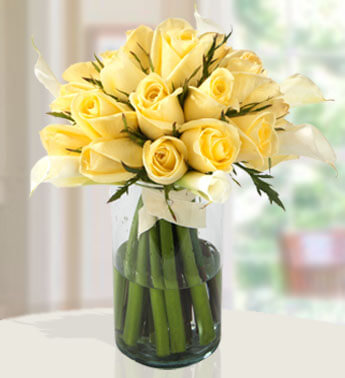 18 stems of Yellow Roses and 10 Calla Lilies in a glass vase. Splashed Sea