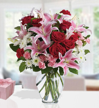 4 stems of Pink Lilies, 6 stems of Red Rose, 8 stems of Pink Carnation, 4 stems of Red Carnation , 2 stems of White Chrysanthemums in a glass vase. (one sided round arrangement) Capture the Beauty