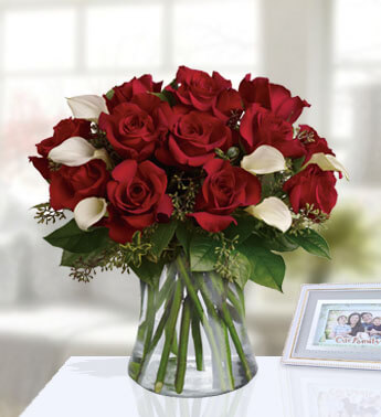 12 red roses and 6 white calla lilies with greenery in a glass vase. Be Still My Heart