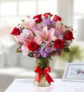 2 stems of Pink Lily, 7 Red Rose, 3 stems of Pink Chrysanthemum in a glass vase. Europe Special