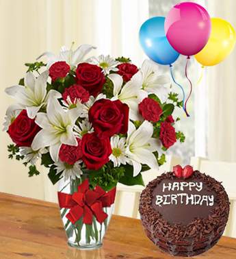 6 Red Carnation, 6 stems of White Chrysanthemum, 4 stems of White Lily, 8 Red Rose in a Glass vase (one sided round arrangement) with 1Kg chocolate Cake and 3 Latex Balloon From My Heart